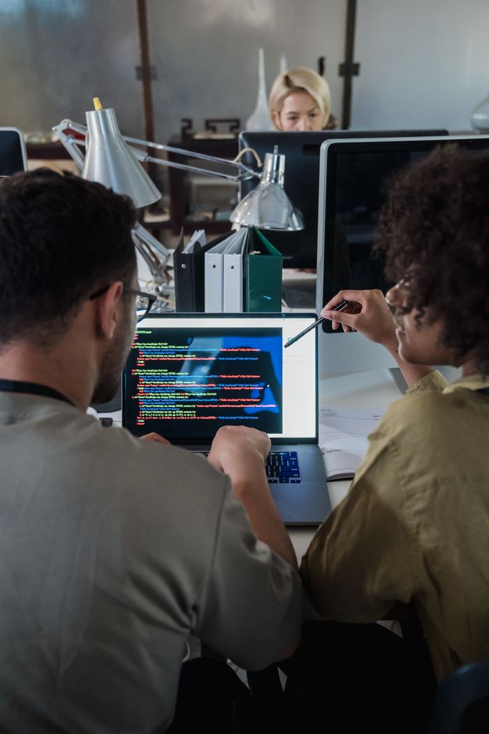 Mastering the First Impression: Your intriguing post title goes here Two developers engage in software programming on a laptop in a modern office setting.